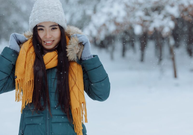 girl wearing a yellow scarf and a white hat with a dark green coat